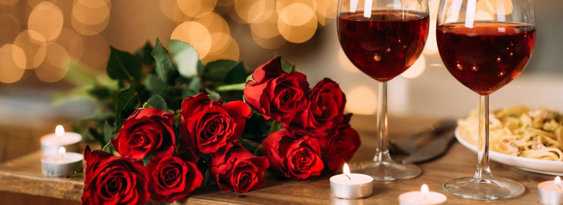 Romantic table setting with roses, wine, and pasta